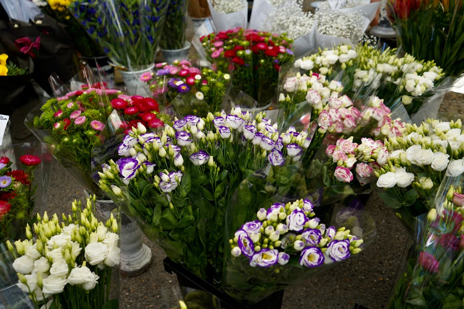 A vibrant display of fresh flower bouquets arranged on a table, featuring a variety of colorful blossoms such as purple and white lisianthus, pink and white carnations, and red and white daisies, all